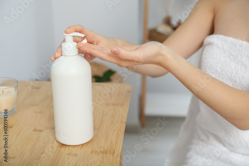 Young woman applying body cream on hands in bathroom  closeup