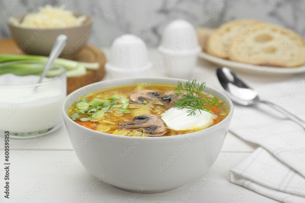 Delicious sauerkraut soup with mushrooms, dill and sour cream served on white table