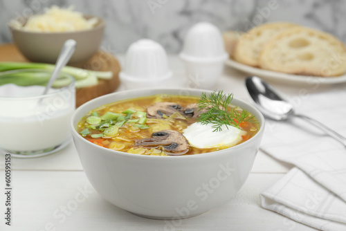 Delicious sauerkraut soup with mushrooms, dill and sour cream served on white table