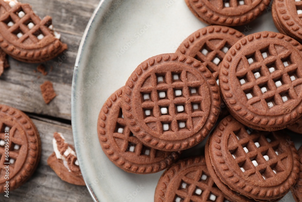 Tasty chocolate sandwich cookies with cream on wooden table, closeup