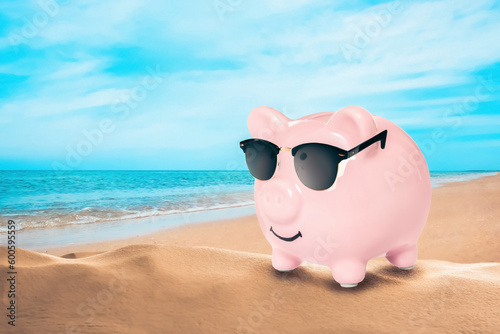 Vacation savings. Piggy bank with sunglasses on sandy beach near sea. Space for text © New Africa