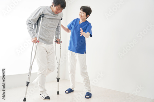 松葉杖を使って歩くリハビリをする中年男性