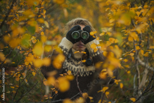 Caucasian woman birdwatching with binoculars autumn forest