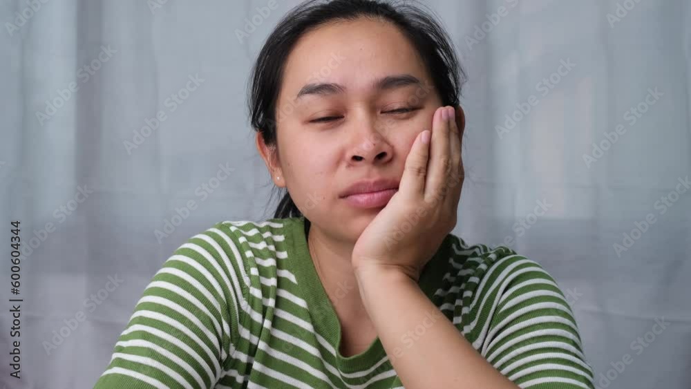 Tired woman yawning covering her mouth with her hands wanting to rest. Portrait of Asian woman with negative expression, tired, yawning, covering her mouth with hands in casual clothes. Tired woman yawning covering her mouth with her hands wanting to rest. Portrait of Asian woman with negative expression, tired, yawning, covering her mouth with hands in casual clothes.