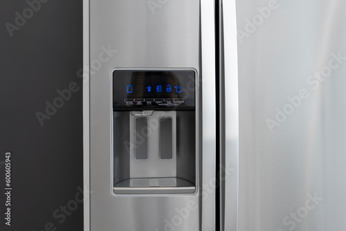 Detail of ice maker and water dispenser on modern refrigerator door.