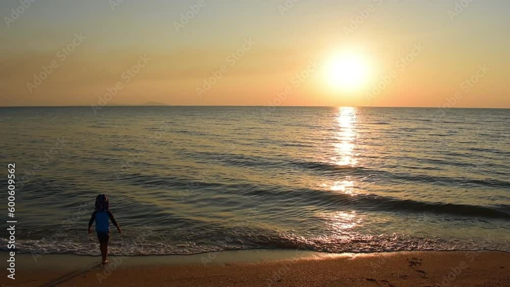 handheld shot, happy child boy playing water sea on the beach with golden sun light of sunset in summer vacation day handheld shot, happy child boy playing water sea on the beach with golden sun light of sunset in summer vacation day