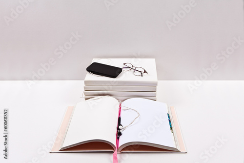 Notebook with smart phone and glasses on the table. White background