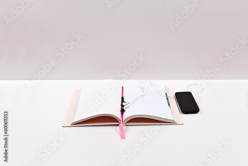 Notebook with earphones and smart phone on a white background.