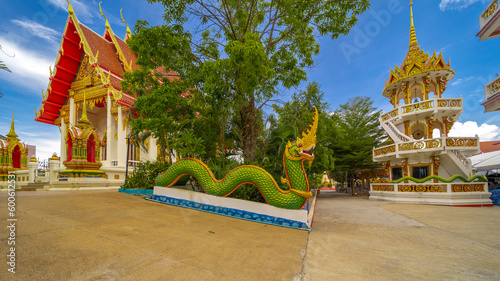 Beautiful Wat Buddhist temple in Phuket Karon Thailand. Decorated in beautiful ornate colours of Gold blue green red and White. Sunset Sunrise lovely sky and cloud colours