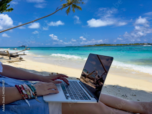 Fototapeta Naklejka Na Ścianę i Meble -  Nomad digital with laptop and running remotely with bright scenic view near poolside on the beach in summer time
