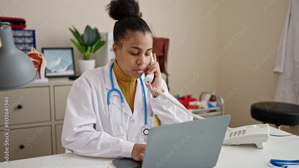 Young african american woman doctor using laptop talking on telephone at clinic Young african american woman doctor using laptop talking on telephone at clinic