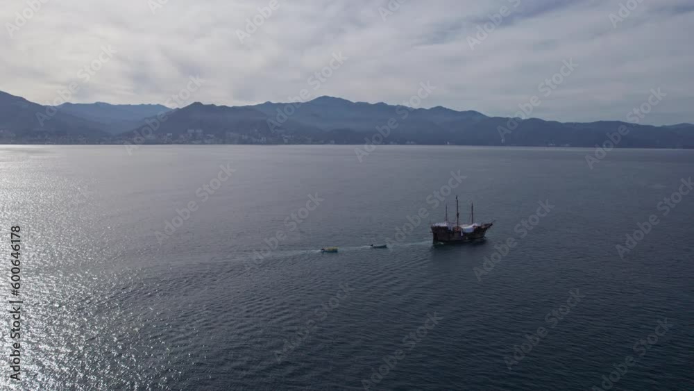 Drone video showing a pirate ship sailing along the coasts of Puerto Vallarta and Banderas Bay, orbiting the impressive vessel, showing the distant shoreline and beautiful backlit sunlight. Drone video showing a pirate ship sailing along the coasts of Puerto Vallarta and Banderas Bay, orbiting the impressive vessel, showing the distant shoreline and beautiful backlit sunlight.