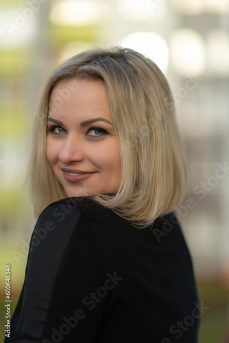 Portrait of a young beautiful blonde girl in a dark dress with a bouquet.