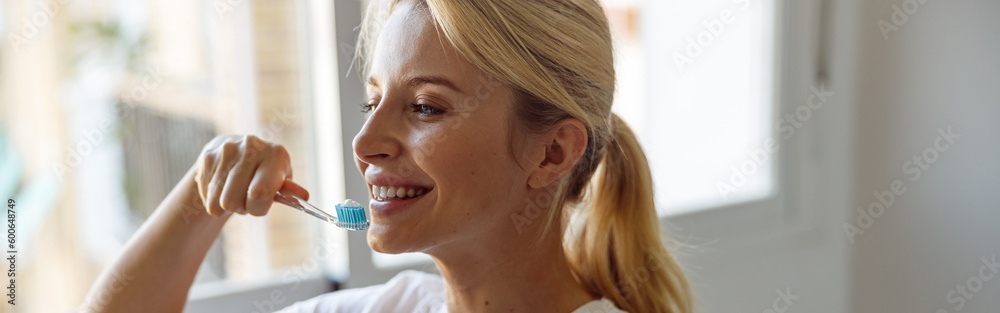 Smiled pretty young blonde woman cleaning teeth with toothbrush in bathroom. taking care. Smiled pretty young blonde woman cleaning teeth with toothbrush in bathroom. taking care.