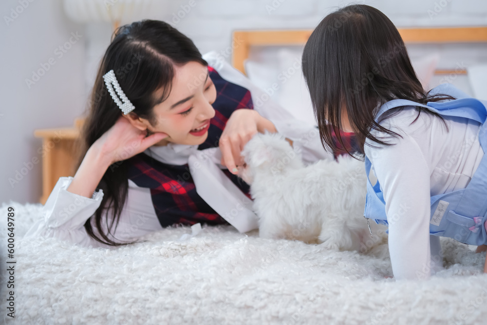 The bond between the little girl and the beautiful asian woman was evident as they lying with their furry friend on the bed in the cozy bedroom The bond between the little girl and the beautiful asian woman was evident as they lying with their furry friend on the bed in the cozy bedroom