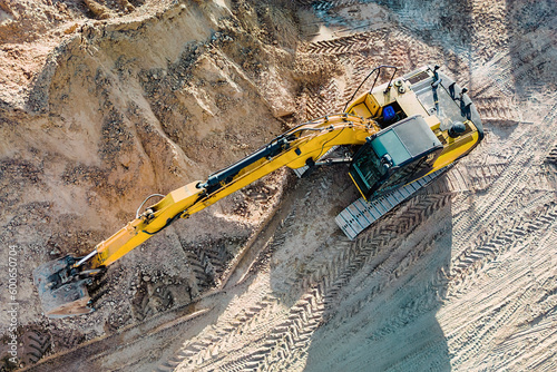 Aerial view of excavator working in quarry or construction site. Industrial top view background concept. A mining excavator is digging a pit. Rental of construction equipment. Contractor.