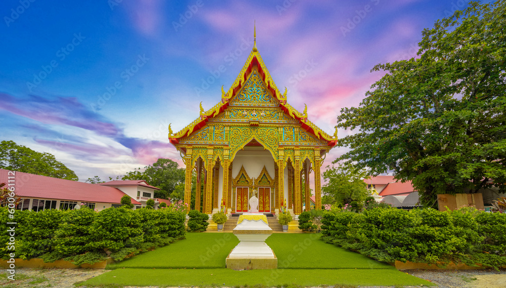 Beautiful Wat Buddhist temple in Phuket Karon Thailand. Decorated in beautiful ornate colours of Gold blue green red and White. Sunset Sunrise lovely sky and cloud colours