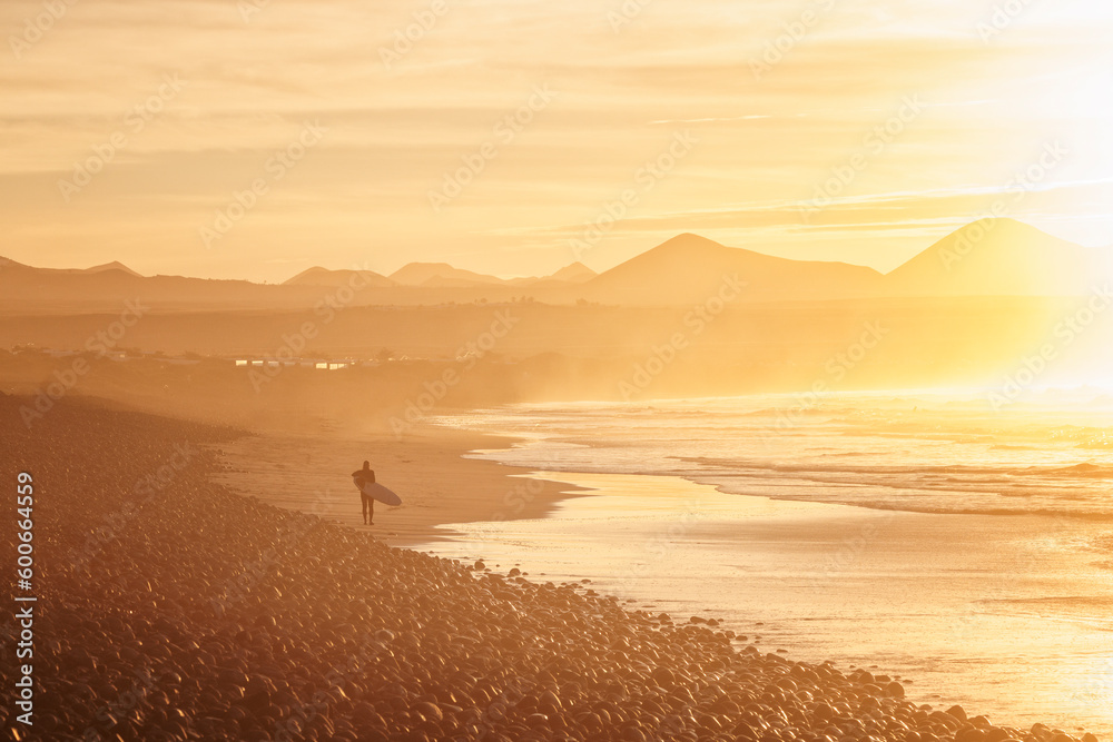 surfer coming out of the water at sunset surfer coming out of the water at sunset