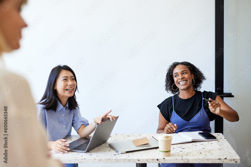 © Cavan Images - Happy female entrepreneurs sitting at desk during meeting at cafe © Cavan Images - Happy female entrepreneurs sitting at desk during meeting at cafe