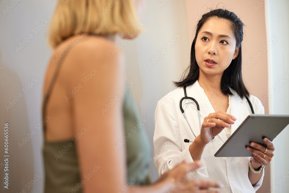 Female doctor holding tablet PC while discussing with patient Female doctor holding tablet PC while discussing with patient