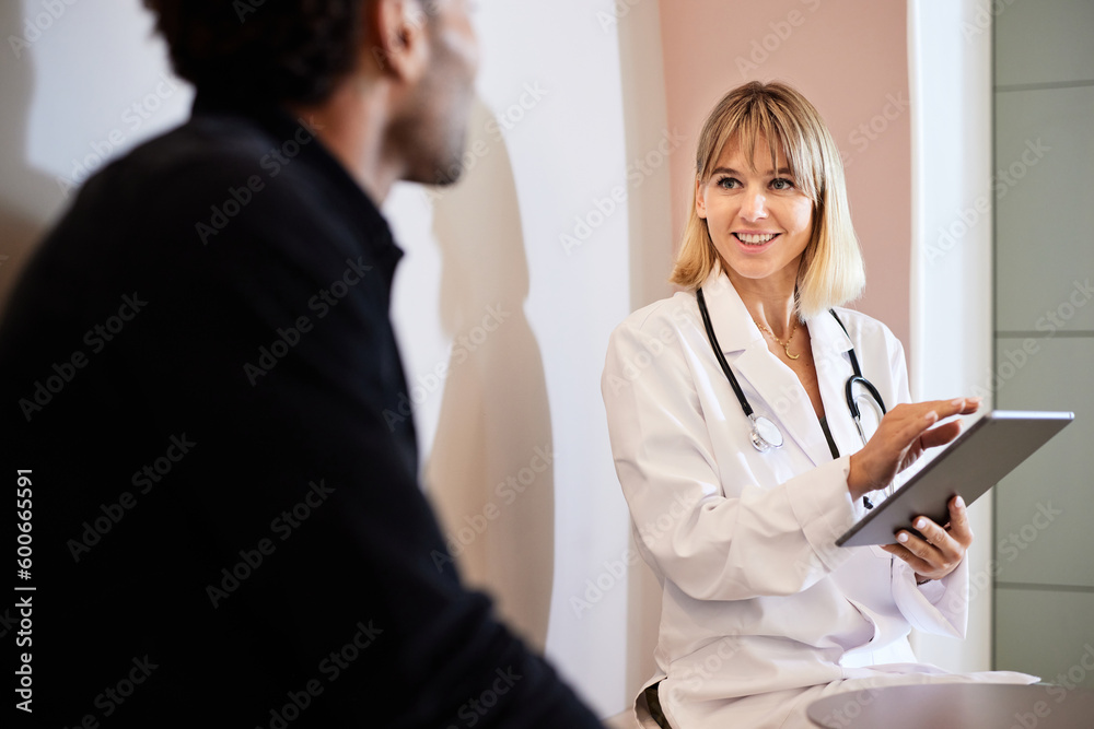 Blond female doctor holding tablet while discussing with male patient Blond female doctor holding tablet while discussing with male patient