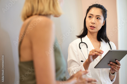 Female doctor holding tablet PC while discussing with patient photo