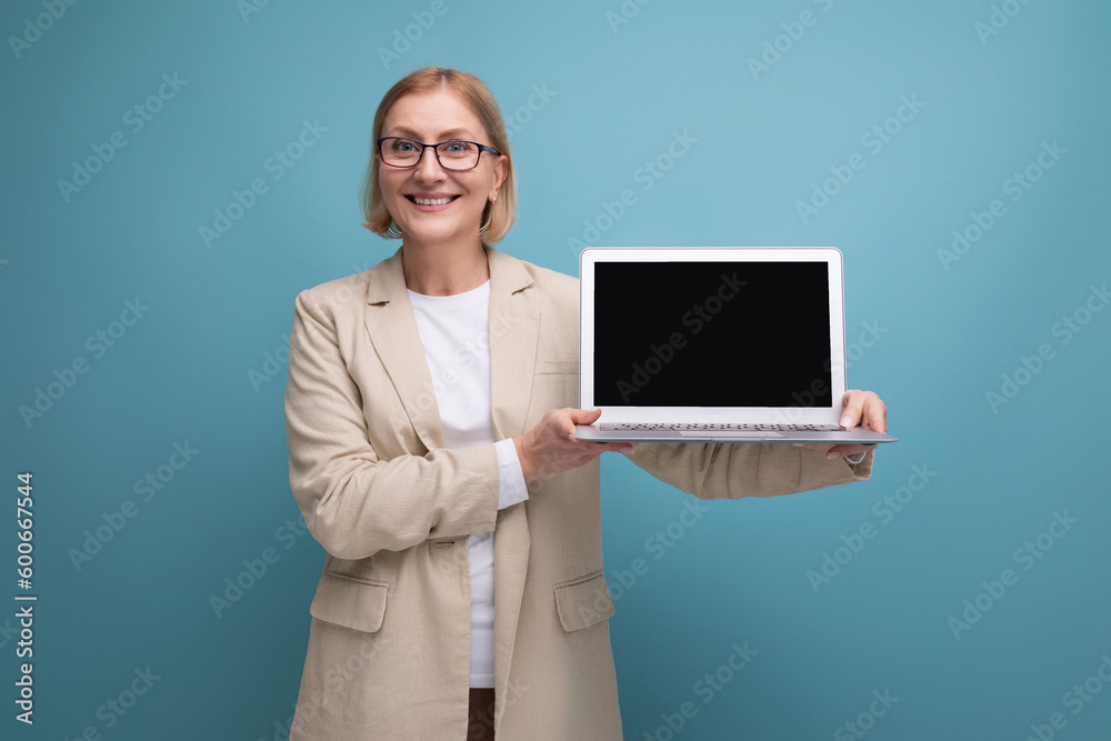 business 50s middle aged woman in a jacket with a laptop to work with a mocap on a studio background with copy space