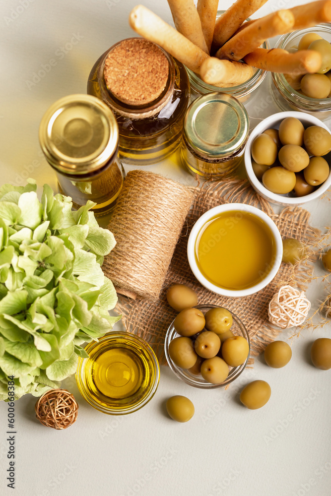 Olive oil, green whole olives in small bowls and grissini in rustic style on light background. Olive oil, green whole olives in small bowls and grissini in rustic style on light background.