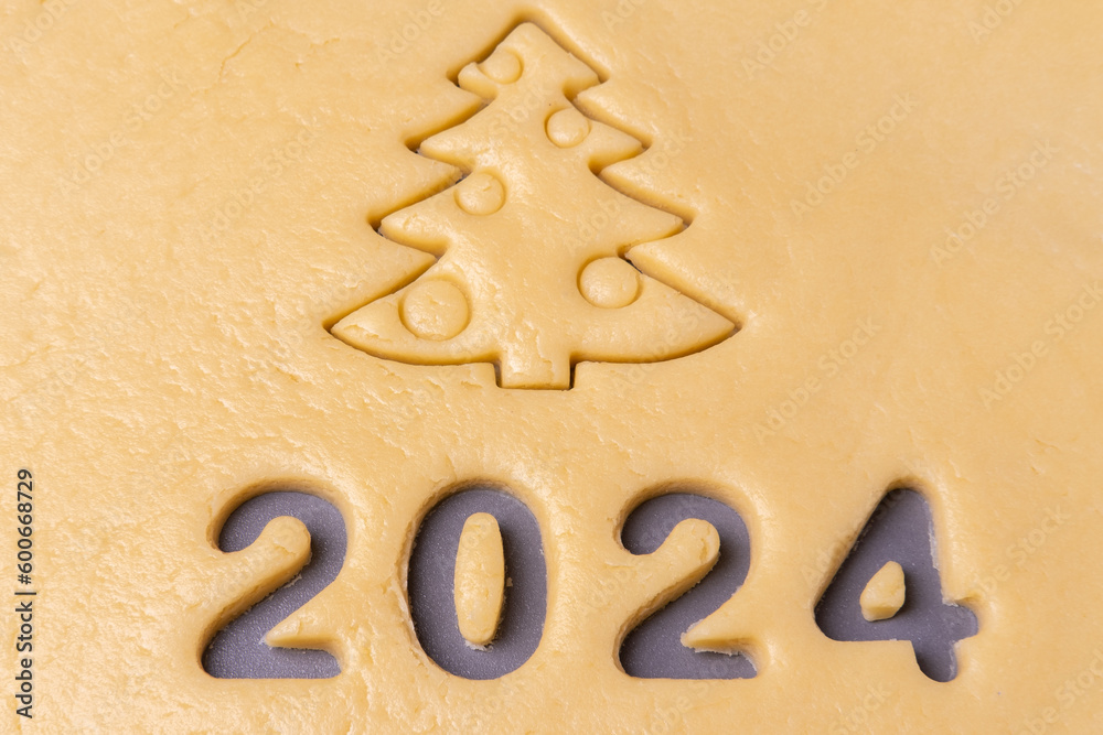 New year 2024. Cooking homemade cookies. Cutting out cookies in shape of the number 2024 and Christmas tree. New year 2024. Cooking homemade cookies. Cutting out cookies in shape of the number 2024 and Christmas tree.