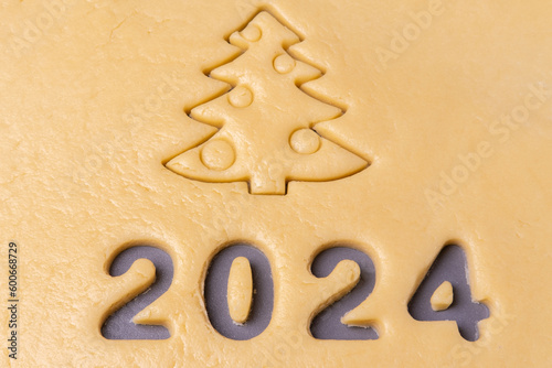 New year 2024. Cooking homemade cookies. Cutting out cookies in shape of the number 2024 and Christmas tree.