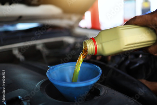Engine oil is being poured into the engine as a change every 10,000 kilometers or maintenance intervals for engine performance and longevity. Preventive maintenance car and engine concept.