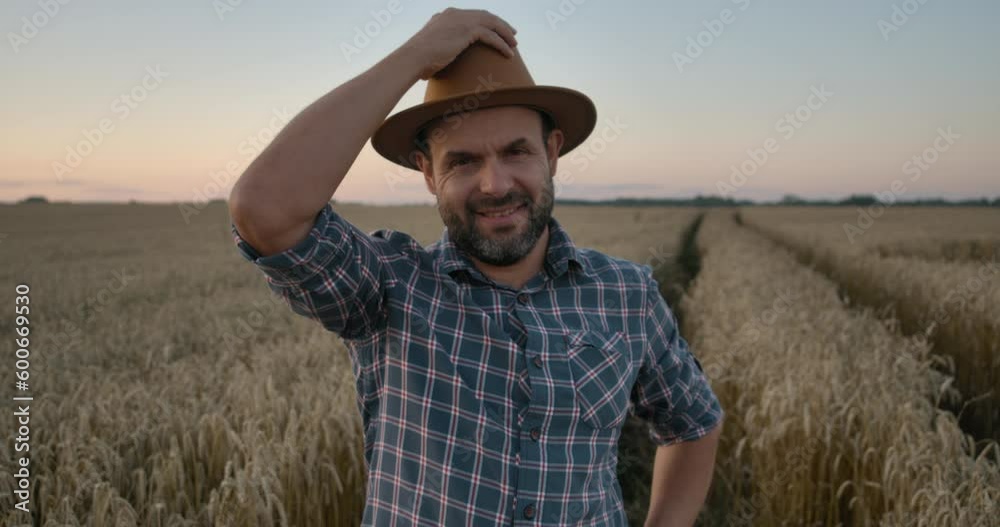 Portrait Farmer Bearded Man With Hat Standing in Wheat Field. Farm Worker. Sunset Sky. Portrait Caucasian Farmer Man in Plaid Shirt in Hat Looking at Camera. Farmland Sunset Landscape Agriculture. Portrait Farmer Bearded Man With Hat Standing in Wheat Field. Farm Worker. Sunset Sky. Portrait Caucasian Farmer Man in Plaid Shirt in Hat Looking at Camera. Farmland Sunset Landscape Agriculture.