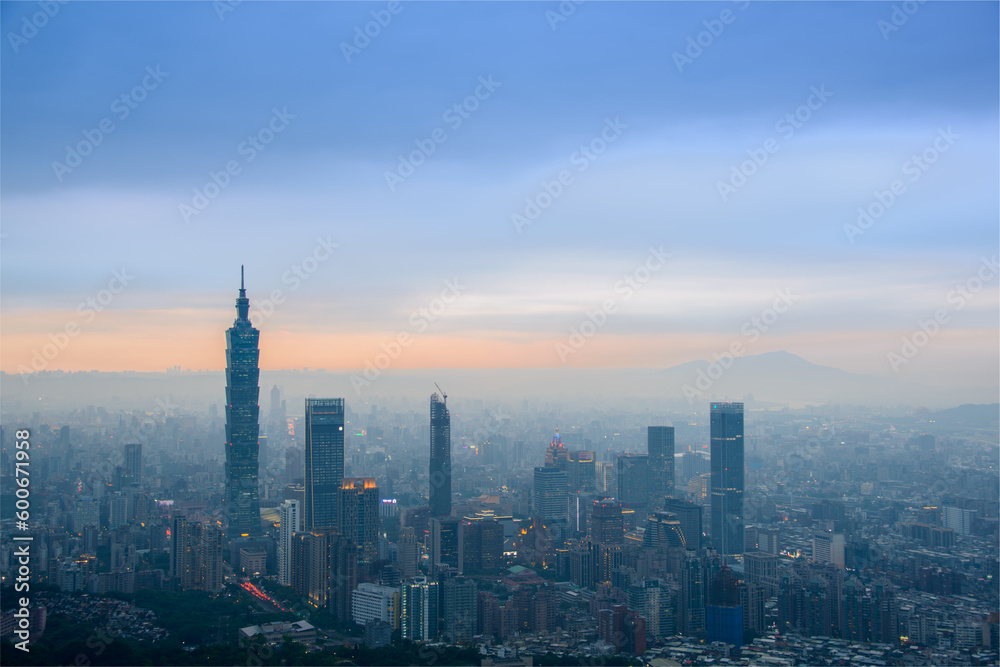 Hazy views of the city and Guanyin Mountain. The sky is blue and orange. Overlooking the city's dazzling landscape at dusk and night. Taipei, Taiwan