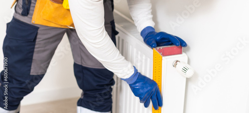 Portrait Of Mid-adult Male Plumber Repairing Radiator With Wrench.