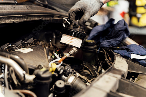 Bilde på lerret An auto mechanic replaces a new fuel filter with a modern diesel engine