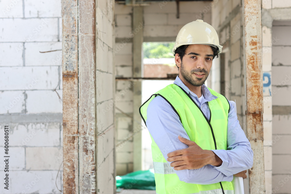 Caucasian technician civil engineer or specialist inspector standing and crossed arms while looking at camera with happy face after project complete at Industrial building site. Construction concept