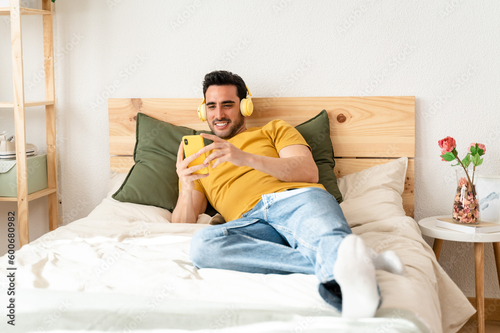 Man lying in bed watching videos with mobile phone.