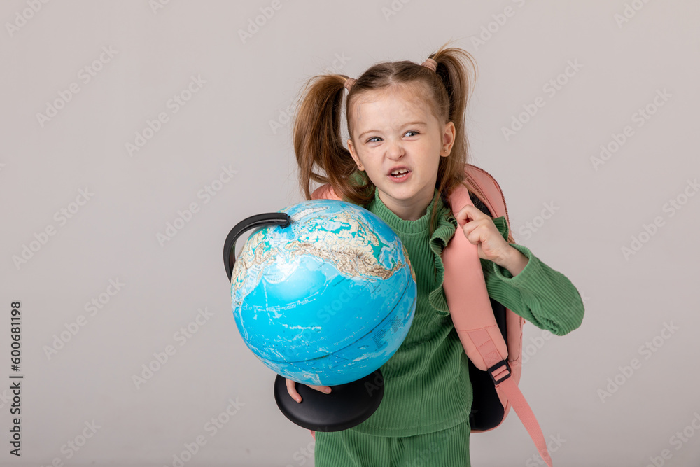 Beautiful kid back to school. Happy cute clever confident girl with go to first grade. Smart schoolchild with pink schoolbag holding globe in hands. Education. Beautiful kid back to school. Happy cute clever confident girl with go to first grade. Smart schoolchild with pink schoolbag holding globe in hands. Education.
