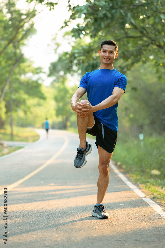 Full length of male athlete in fitness clothes doing stretching exercise, preparing for morning workout