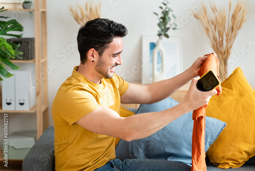 Smiling man in living room holding new t-shirt. photo