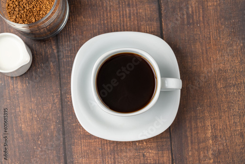 Instant or granulated coffee in white cup on wooden table