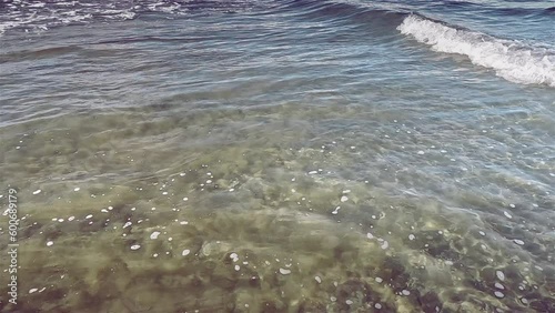 Oncoming sea wave slow motion. Beautiful waves on shore with foam and murmur. Ripples on the water, yellow sea color and Mixing sand
