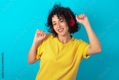 фотографія Carefree young arab woman wearing yellow T-shirt over blue background with tooth
