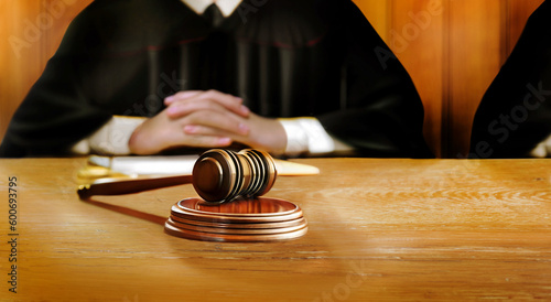 Judge's hammer symbolizes the judgment on the judicial wooden table in courtroom