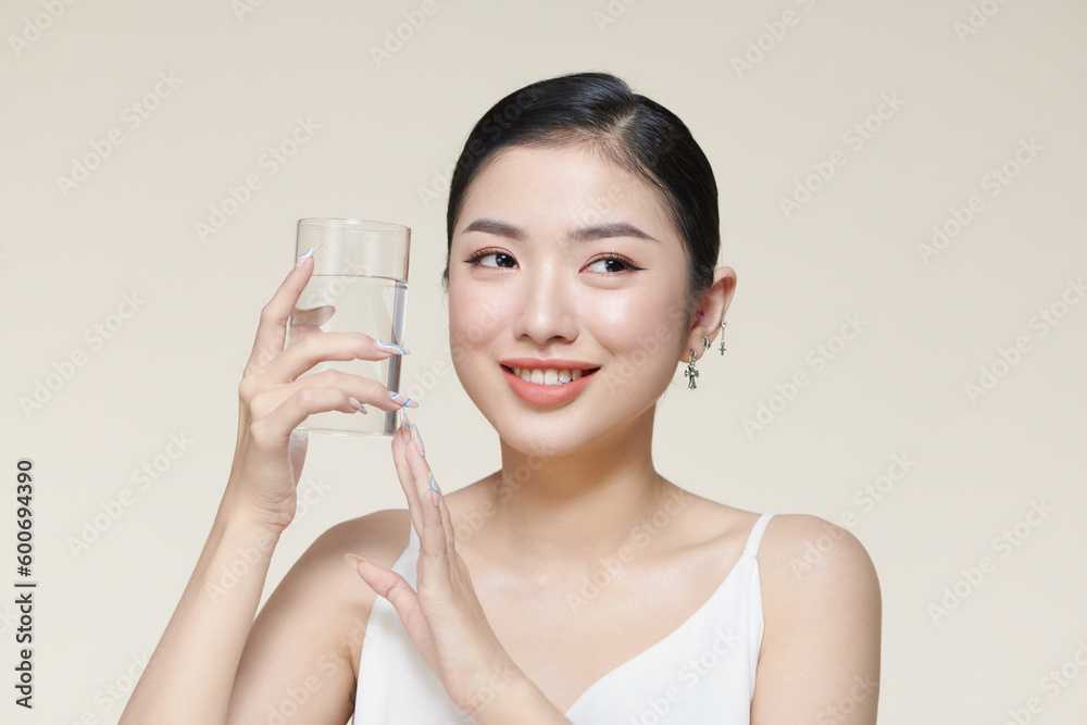 Asian woman drinking water on beige background Asian woman drinking water on beige background