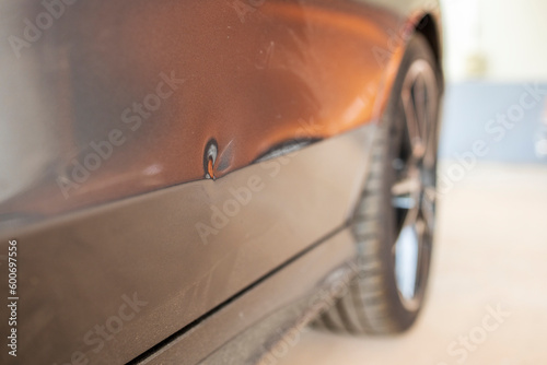 Car dent after traffic accident or crash.Deformity lesion on the rear door of grey vehicle with space.Rear wheel with blur background and space.Insurance prompt to repair the car dent.Small dent.