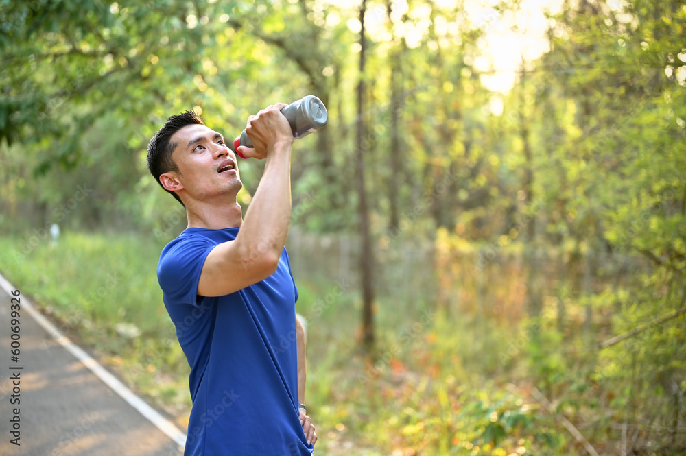 Thirsty and tired Asian male runner in sportswear drinks water from a bottle while running Thirsty and tired Asian male runner in sportswear drinks water from a bottle while running