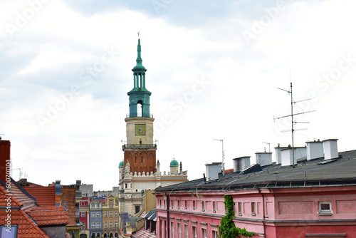 City view of the old buildings with red roofs, and a town hall on the light blue sky background. Central square, old market with historical buildings. Poland, Poznan, June 2022