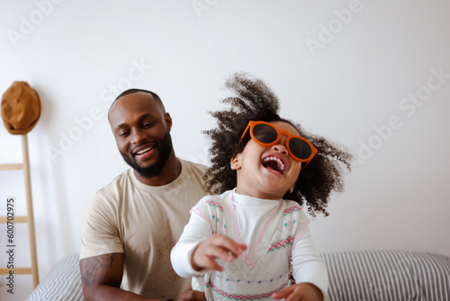 Happy caring African American family young dad father and small cute child daughter portrait, loving black dad and little mixed race kid girl bonding on fathers day