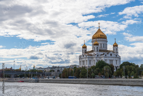 Side view of Cathedral of Christ the Saviour standing on Moscva river embankment. Blue sky with white clouds. Copy space for your text. Religious architecture. Travel in Russia theme.